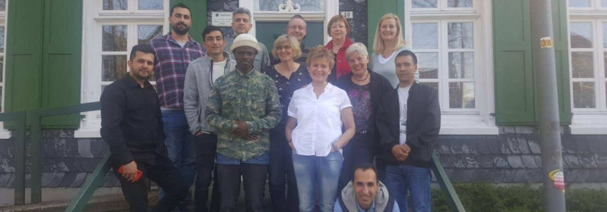 Café International - Besucher vor dem Haus an der Kirche